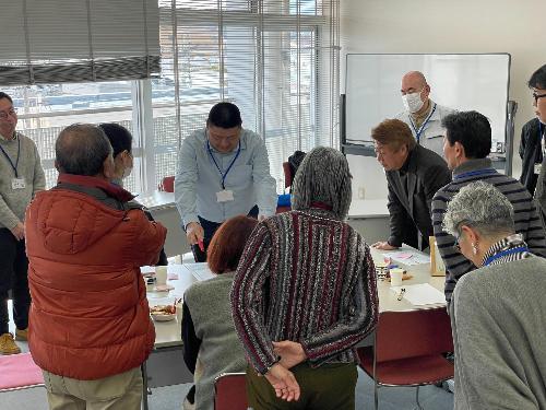 参加者が机を囲んで発表を聞いている様子