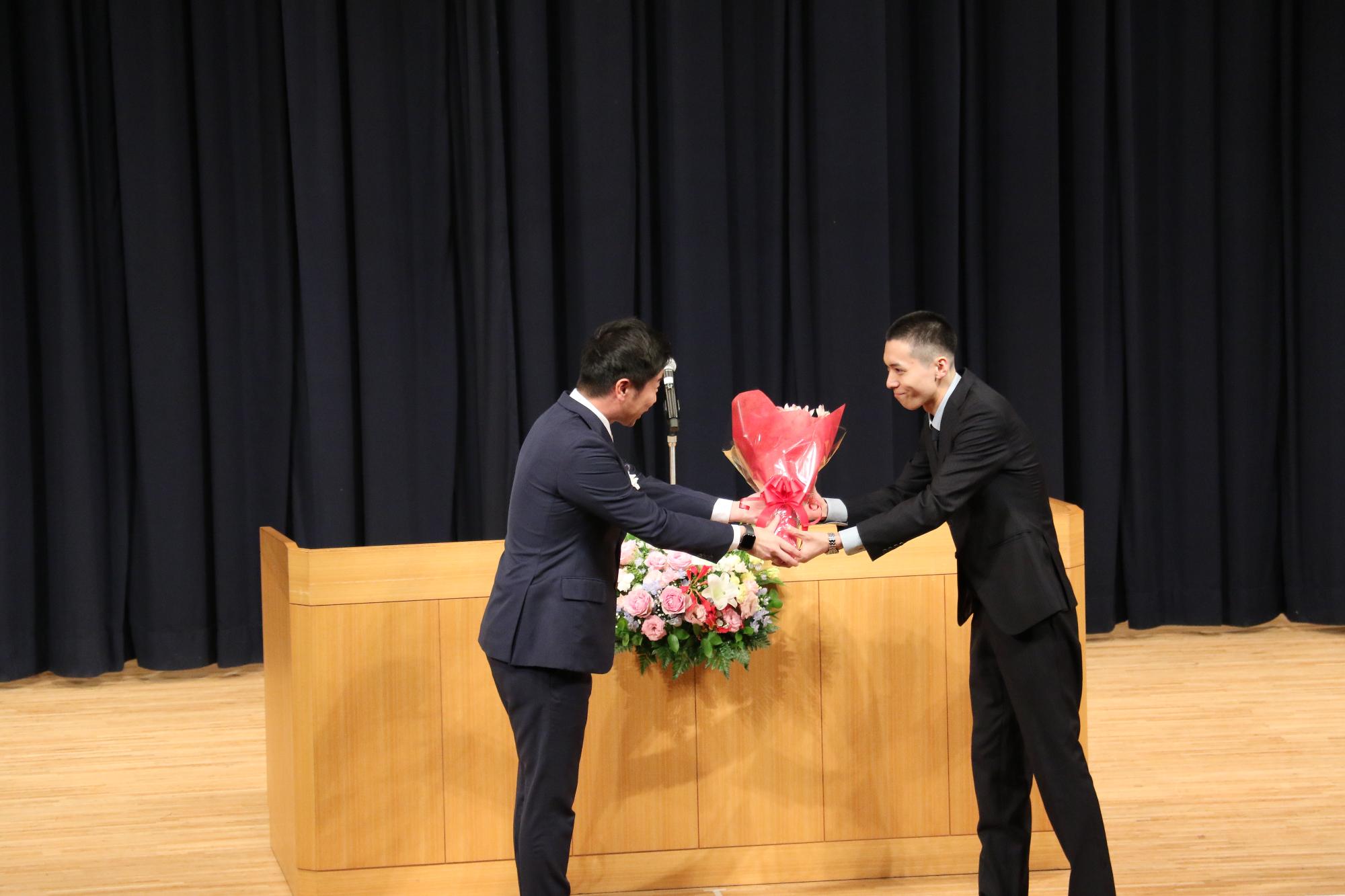 花束を渡す山本市長と受けとる実行委員の様子