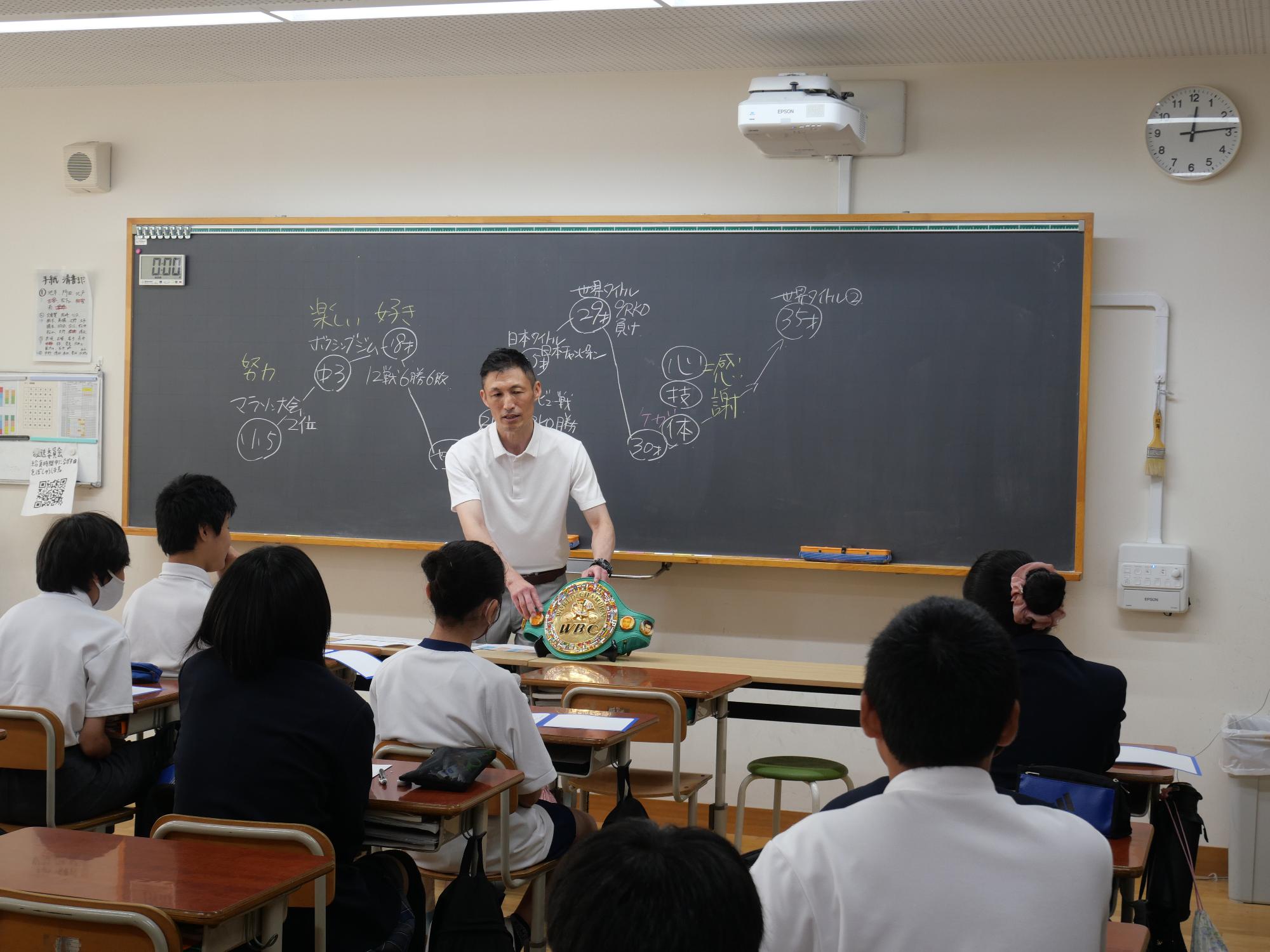 チャンピオンベルトを生徒に見せる越本隆志氏